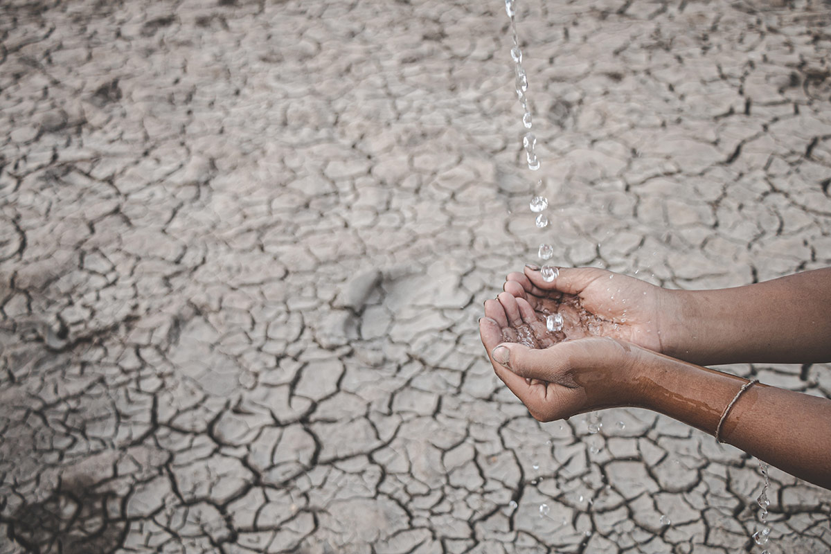 cropped-image-hand-holding-water-against-barren-land